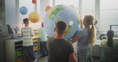 Ekoloji BTMM Sınıfı: İlkokul öğrencileri Dünya 'ya Bulutların Minyatür Modelleri Ekliyor. Modern Sınıfta Dünya Gezegeni Modelini kullanarak Bilim ve Yenilenebilir Enerji Kaynakları Çalışan Zeki Çocuklar.