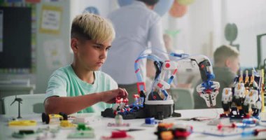 Masada oturan yetenekli genç çocuk, Erkek Öğretmenle Robotik Kol Modeli okuyor. Modern Sınıfta İlkokul Öğrenim Mühendisliği, Bilim ve Robot Teknolojisi. STEM Eğitimi.