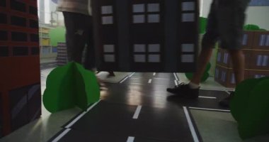 Düşük Açı Çekimi İlkokul Öğrencileri Hardhat Hareketli Bloklar, Şehir Planlama Ekibi. Geniş Mukavva Şehir Modelleri, Yolları, Ağaçları ve Binaları olan yaratıcı STEM sınıfı. El bilgisayarı.