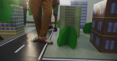 Karton Şehir Modelleri, Binalar, Yollar, Ağaçlar ile Etkileşimli Şehir Planlaması Yapan Akıllı Genç Çocukların Düşük Açı Çekimi. İlkokul çocukları için sınıf etkinliği. BTMM Öğrenme. El bilgisayarı.