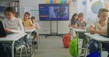 İlkokul öğrencileri dizüstü bilgisayarlarda yaratıcı projeler üzerinde çalışıyor, Sanat sınıfında dijital beceriler geliştiriyor. Resim Oluşturmak için Yapay Zeka Yazılımını Gösteren Dijital Ekran. İnteraktif STEM Öğrenme. Doli Vuruşu