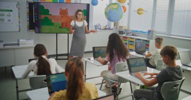 Genç Öğrencileri Eğiten, Dijital Ekranda Yaratıcı Öğrenim Gösteren Öğretmen. İlkokul çocukları sınıftaki dijital sanat dersinde dizüstü bilgisayarlara resim çiziyor. Etkileşimli BTMM Eğitimi.