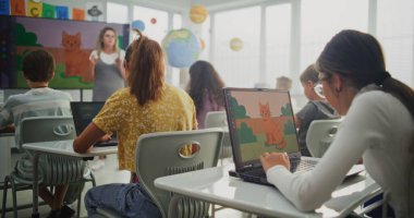 İlkokul öğrencileri Modern Sınıfta Dizüstü bilgisayarlarda Dijital İllüstrasyonlar Yaratıyorlar. Dijital Ekran kullanarak Sanat Dersinde Genç Çocuklara Öğretmek. BTMM Yaratıcılık ve Hayal Gücü Öğrenme.