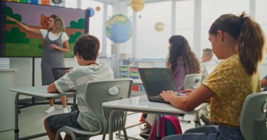 İlkokul çocukları sınıftaki dijital sanat dersinde dizüstü bilgisayarlara resim çiziyor. Genç Öğrencileri Eğiten, Dijital Ekranda Yaratıcı Öğrenim Gösteren Öğretmen. Etkileşimli BTMM Eğitimi.