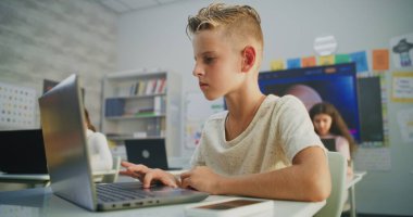 İlkokul çocuğu dizüstü bilgisayarda Yaratıcı Proje üzerinde çalışıyor, Sanat sınıfında Dijital Yetenek Uygulaması yapıyor. Modern Sınıfta Genç Çocuklar Çiziyor, Dijital Aygıtlar Üzerine Görevler Yapıyor. Etkileşimli BTMM Öğrenme.