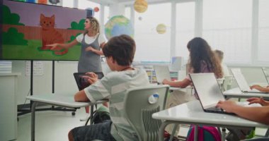 İlkokul çocukları sınıftaki dijital sanat dersinde dizüstü bilgisayarlara resim çiziyor. Genç Öğrencileri Eğiten, Dijital Ekranda Yaratıcı Öğrenim Gösteren Öğretmen. Etkileşimli BTMM Eğitimi.