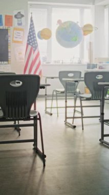 Amerikan İlköğretim Okulu: Öğrenciler için Masaları, Çember tahtası, Güneş Sistemi Asma Modelleri ve Renkli Posterleri olan Boş Sınıfın İçi. Çocukların Çalışması İçin Yaratıcı Alan. Dikey Çekim.