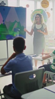 Coğrafya Sınıfı: Dijital Ekran Kullanarak İlkokul Çocuklarına Öğretmenlik Yapan Kadın Öğretmenler. Oturan, Su Döngülerini Öğrenen, Sınıfta Hava Durumu Faktörleri Grubu. Dikey Çekim.