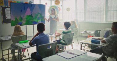 Coğrafya Sınıfı: Dijital Ekran Kullanarak İlkokul Çocuklarına Öğretmenlik Yapan Kadın Öğretmenler. Genç Erkekler ve Kızlar Masada Oturuyor, Modern Sınıfta Su Döngüleri ve Hava Durumu Faktörlerini Öğreniyor