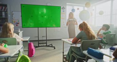 Modern Sınıfta İlköğretim Okulu Öğrencilerini Eğiten Tablet Bilgisayar Öğretmeni. Büyük Dijital Ekran ve Chroma Key Mock Up. Eğitim İçeriği için Yeşil Ekran Şablonu.