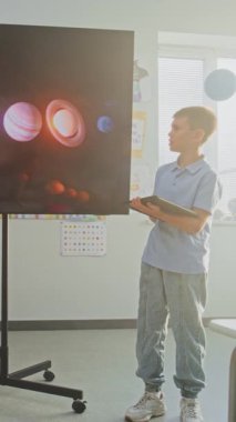 Tablet Bilgisayarlı İlkokul Çocuğu Sınıf Arkadaşları ve Öğretmen Dijital Ekran Kullanıyor 'da Güneş Sistemi ve Gezegenler Hakkında Sunum Yapıyor. Çocuklar Uzay Astronomisi okuyor. Dikey Çekim.