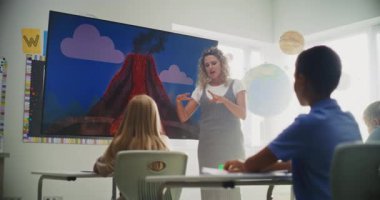 İlköğretim Okulu Öğrencileri Modern Sınıfta Jeoloji Hakkında Temel Bilgiler Çalışıyor. Sayısal Ekran Kullanımı sırasında Zeki Çocuklara Volkanik Patlama Sürecini Açıklayan Bayan Öğretmen.