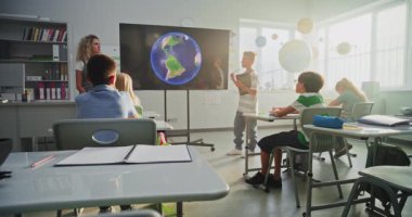 Tablet Bilgisayarlı İlkokul Çocuğu Sınıf Arkadaşları ve Öğretmen Dijital Ekran Kullanıyor 'da Güneş Sistemi ve Gezegenler Hakkında Sunum Yapıyor. Sınıfta Uzay Astronomisi okuyan Zeki Çocuklar.