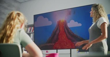 Dijital Ekran Kullanan İlkokul öğrencilerine Temel Jeoloji Bilgilerini Açıklayan Bayan Öğretmen. Sınıf arkadaşlarının önünde duran genç çocuk volkanik patlamayla ilgili soruları cevaplıyor..