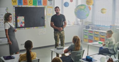 Askeri Subay, Askeri Bilimler ve Disiplin hakkında Meraklı Öğrencilere Konuşan Sınıf Ziyareti. Yakınlarda duran öğretmen, İlköğretim Okulu Kariyer Eğitimi Dersinde Dinleyen Çocuklar