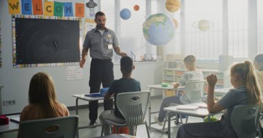 TSA Güvenlik Subayı İlköğretim Okulundaki Genç Öğrencilere Güvenlik Kurallarını Açıklıyor. Çocuklar Sorular Soruyor, Polis İşçi Rehberliğini Dinliyor Hukuk ve Sorumluluk Bilgisi Hakkında.