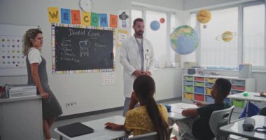 Erkek Sağlığı Profesyoneli Diş Bakımı Meraklı Genç Öğrencilere Açıklama Kuralları. Çocuklar İlköğretim Okulu 'nda Sağlık ve Hijyen Dersinde Soru Soruyor, Dişçiyi Dikkatle Dinliyor.