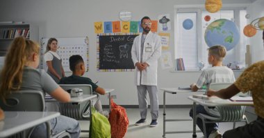 Diş Bakımını Açıklayan Profesyonel Sağlık Kuralı Meraklı Genç Öğrencilere Soruları Yanıtlıyor. İlkokulda Sağlık ve Hijyen Dersinde Dişçi Dinleyen Çocuklar. Yavaş Hareket.