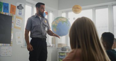 Erkek Polis Ziyaret Sınıfı, Meraklı İlkokul Öğrencilerine Güvenlik Kuralları Konulu Konferans Vermek, Soruları Cevaplamak. Genç Çocuklar Polis Memurunu Dinliyor, Hukuk ve Koruma Hakkında Öğreniyor.