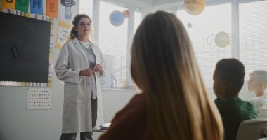 Bayan Doktor Ceket Ziyaret Sınıfı İlkokul Öğrencilerine Sağlık ve Hijyen Konusunda Ders Veriyor. Oturan ve Sağlık Hizmetleri Profesyoneli Dinleyen Genç Çocuklar. Temel Tıp Eğitimi.