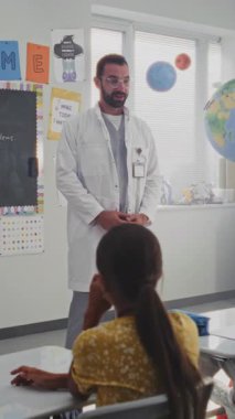 Erkek Sağlığı Profesyonel Diş Bakımı Genç Öğrencilere Açıklama Kuralları. Çocuklar soru soruyor, İlköğretim Okulu 'nda sağlık ve hijyen dersi sırasında diş hekimini dinliyor. Dikey Çekim.