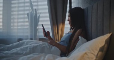 Yatak Bakışlı Genç Asyalı Kadın Sosyal Medya İçeriği. Kadın Asyalı Okuma Haberleri, Pozitif Duyguları Anımsatan Görünümler. Yatak, Çevrimiçi İletişim, Dijital Yaşam Tarzı Konsepti.