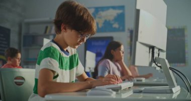 Genç Öğrenci Çizgili Tişört Parlak Sınıfta Bilgisayar 'da çalışıyor. Arka planda Teknolojiyle Öğrenen Çocuklar Grubu. Modern Eğitim, E-öğrenme ve Sınıf Yeniliği. El bilgisayarı.