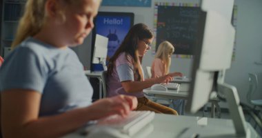 Sunlit Sınıfı 'nda Bilgisayar Klavyesinde Yazan Genç Kız. Onun arkasında, çocuklar sessizce masalarda çalışıyor. Modern Eğitim, Öğretim Teknolojisi, Konsantrasyon, Akademik Büyüme Konsepti. El bilgisayarı.