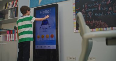 Çocuk, Al 'ın ruh hali izleyicisiyle neşeli bir şekilde etkileşim kuruyor. Sınıfta Öğrenciler Olumlu Duygular Gösteriyor. Eğitim Teknolojileri, Duygusal Zeka Geliştirme ve Çocuk Akıl Sağlığı Bakımı. El bilgisayarı.