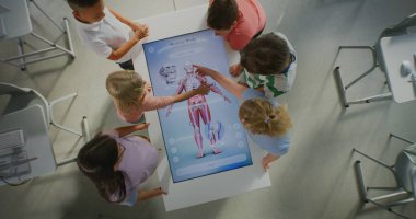 Parlak Sınıftaki Öğrenciler İnsan Vücudunun Etkileşimli Görünümünü Gösterirken Birlikte Çalışıyor. Çocuklar Ekrana Dokunur, Kasları Öğrenir. Konsept Bilim Eğitimi, Gelecek Teknolojisi. Üst Görünüm Döndürülüyor.