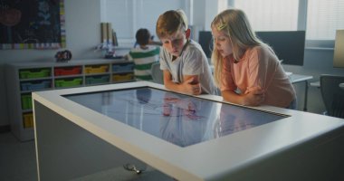 Sınıfta Dokunmatik Ekran Masası 'nda Çocuklar Kas Sistemi Üzerinde Çalışır. Öğrenciler İletişim Kurar, Fikirleri Paylaşır, 3D Anatomi Modelini Birlikte Keşfeder. İnteraktif Öğrenme kavramı, BTMM Eğitimi. Doli Vuruşu.