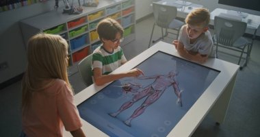 Üç Okul Çocuğu İnsan Anatomisi 'nin 3 Boyutlu Modelini Göstererek Birlikte Çalışıyor. Modern Eğitim ve Dokunmatik Ekran Teknolojisinin Bilim ve Biyoloji Dersleri Konsepti. Doli Vuruşu.
