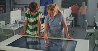 Avrupa Okul Çocukları Dijital Dokunmatik Masa Kullanarak Anatomi Projesini Tartışıyor. Sınıf arkadaşlarıyla Modern Sınıflar Ortamı. İnteraktif Öğrenme ve BTMM Eğitimi kavramı. El bilgisayarı.