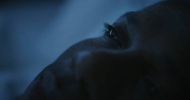 Soğuk Gece Işığıyla aydınlatılan Mans Face 'in Kapanışı. Afrikalı Amerikalı adam zor bir günün ardından yavaşça uykuya dalıyor. Uykusuzluk, Yoksul Dinlenme, Endişe ve Uykusuz Geceler kavramı. Sabit Çekim.