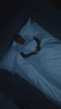 Smartphone 'da Yatak Odası' nın dışında patlamalar olurken Yatak Haberleri 'ndeki adam. Geceleri, Adam patlamalardan paniğe kapılır. Hava saldırısı sirenleri. Stres, Uykusuzluk. Dikey Çekim.