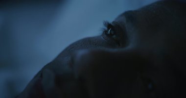 Soğuk Gece Işığıyla aydınlatılan Mans Face 'in Kapanışı. Afrikalı Amerikalı adam zor bir günün ardından yavaşça uykuya dalıyor. Uykusuzluk, Yoksul Dinlenme, Endişe ve Uykusuz Geceler kavramı. Sabit Çekim.