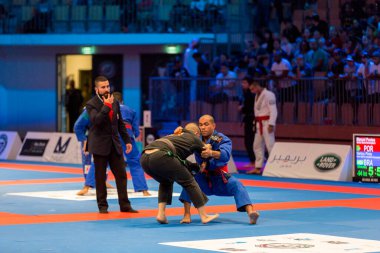 ABU DHABI, UAE - 19 Nisan 2016: ABU DHABI World PROFESSIAL JIU-JITSU CHAMPIONSIP 2016, IPIC ARENA. Siyah ve mavi kimonolu dövüşçüler dövüşüyor..