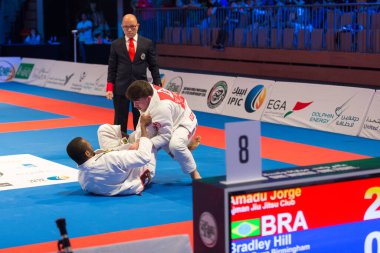 ABU DHABI, UAE - 19 Nisan 2016: ABU DHABI World PROFESSIAL JIU-JITSU CHAMPIONSIP 2016, IPIC ARENA. Kahverengi kemerli dövüşçüler. Hakem onların yanında..