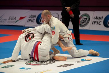 ABU DHABI, UAE - 19 Nisan 2016: ABU DHABI World PROFESSIAL JIU-JITSU CHAMPIONSIP 2016, IPIC ARENA. Mor kemerli dövüşçüler parterre içinde dövüşüyor..