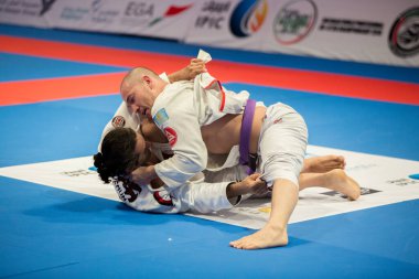 ABU DHABI, UAE - 19 Nisan 2016: ABU DHABI World PROFESSIAL JIU-JITSU CHAMPIONSIP 2016, IPIC ARENA. Mor kemerli dövüşçüler parterre içinde dövüşüyor..