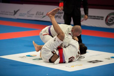 ABU DHABI, UAE - 19 Nisan 2016: ABU DHABI World PROFESSIAL JIU-JITSU CHAMPIONSIP 2016, IPIC ARENA. Mor kemerli dövüşçüler parterre içinde dövüşüyor..