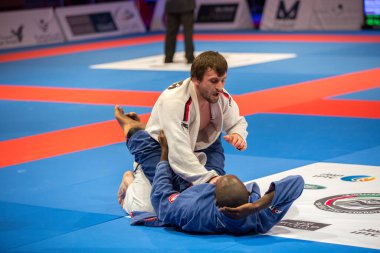 ABU DHABI, UAE - 19 Nisan 2016: ABU DHABI World PROFESSIAL JIU-JITSU CHAMPIONSIP 2016, IPIC ARENA. Beyaz ve mavi kimonolu dövüşçüler parterre içinde dövüşüyor..
