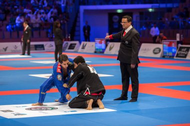 ABU DHABI, UAE - 19 Nisan 2016: ABU DHABI World PROFESSIAL JIU-JITSU CHAMPIONSIP 2016, IPIC ARENA. Dövüşçüler. Mavi ve siyah kimonolu adamlar kavga ediyor. Hakem siyah kimonolu dövüşçüye bir puan veriyor..