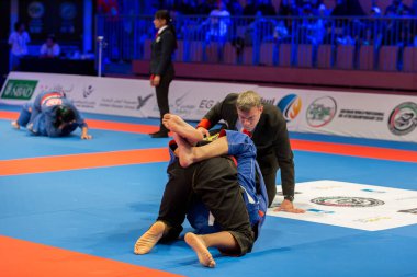 ABU DHABI, UAE - 19 Nisan 2016: ABU DHABI World PROFESSIAL JIU-JITSU CHAMPIONSIP 2016, IPIC ARENA. Hakem, parterdeki dövüşçüleri takip ediyor..