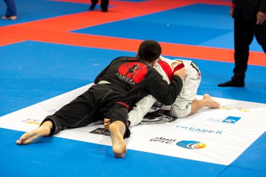 ABU DHABI, UAE - 19 Nisan 2016: ABU DHABI World PROFESSIAL JIU-JITSU CHAMPIONSIP 2016, IPIC ARENA. Beyaz ve siyah kimonolu adamlar Parterre 'de kavga ediyor..