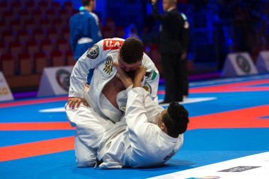 ABU DHABI, UAE - 19 Nisan 2016: ABU DHABI World PROFESSIAL JIU-JITSU CHAMPIONSIP 2016, IPIC ARENA. Beyaz kemerli dövüşçüler paspasın üzerinde dövüşüyor..