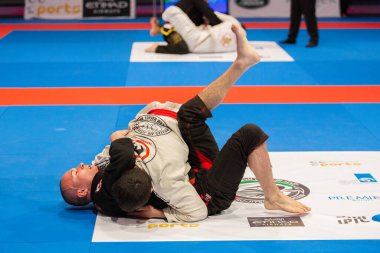 ABU DHABI, UAE - 19 Nisan 2016: ABU DHABI World PROFESSIAL JIU-JITSU CHAMPIONSIP 2016, IPIC ARENA. Mavi hasırda dövüşçüler.