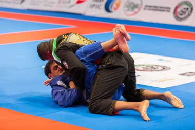 ABU DHABI, UAE - 19 Nisan 2016: ABU DHABI World PROFESSIAL JIU-JITSU CHAMPIONSIP 2016, IPIC ARENA. Siyah-mavi kimonolu dövüşçüler paspasın üzerinde dövüşüyor..