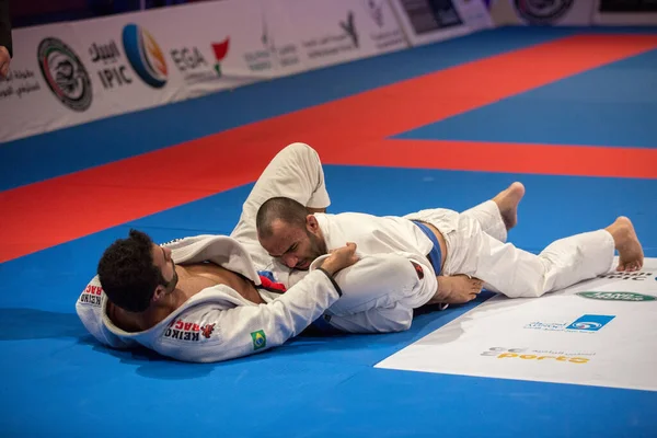 ABU DHABI, UAE - 19 Nisan 2016: ABU DHABI World PROFESSIAL JIU-JITSU CHAMPIONSIP 2016, IPIC ARENA. Beyaz kimonolu iki dövüşçü parterre 'de dövüşüyor..