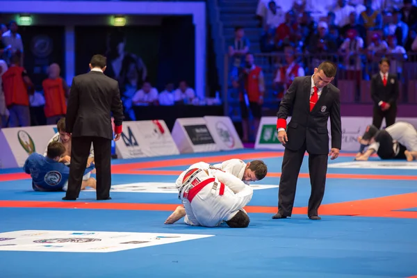 ABU DHABI, UAE - 19 Nisan 2016: ABU DHABI World PROFESSIAL JIU-JITSU CHAMPIONSIP 2016, IPIC ARENA. Boksörler paspasın üzerinde dövüşüyor. Yanlarında hakem var..